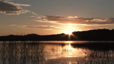 Time lapse sunrise over forest hillside on beautiful morning at calm lake.