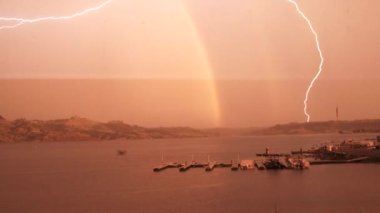 Huge lightning strike and loud thunder during heavy rain storm over lake by boat docks, sound included.