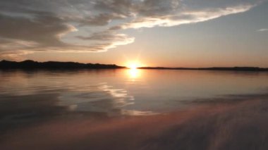 From the back of fast speed boat point of view while cruising at lake during sunset.