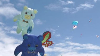 Large size kites flying in the breeze on sunny blue sky day.
