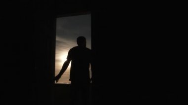 Sequence of person opening door, walking out into beautiful sunny sky then walking back in room closing door transition to black frame.