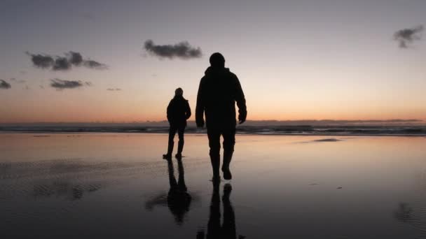 Czarnego Przejścia Człowiek Wychodzi Żony Stojąc Refleksyjnej Piaszczystej Plaży Zachodzie — Wideo stockowe