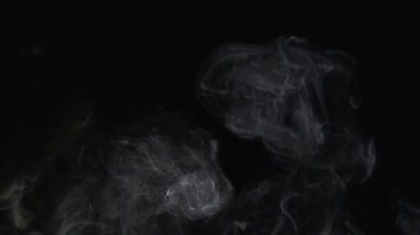 Dumanın arka plan etkisi yarı hızda yavaş çekimde siyaha karşı yükseliyor.