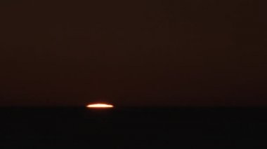 Sıcak ve berrak gökyüzünde, okyanus ufkunda, gece gündüz gün doğumunun hızlanması..