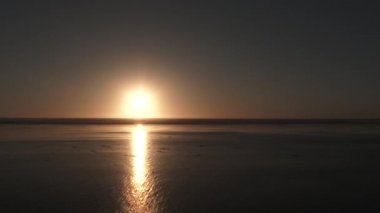 Okyanus ufkunun altındaki güneş kumlu sahilden geniş açılı..