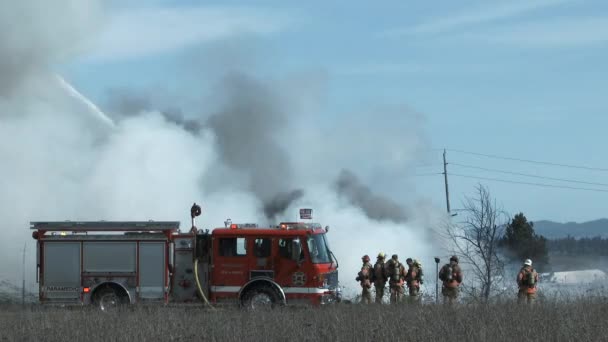 当野火熄灭时 一队消防队员站在旁边 看着火势从消防车转成浓烟 — 图库视频影像