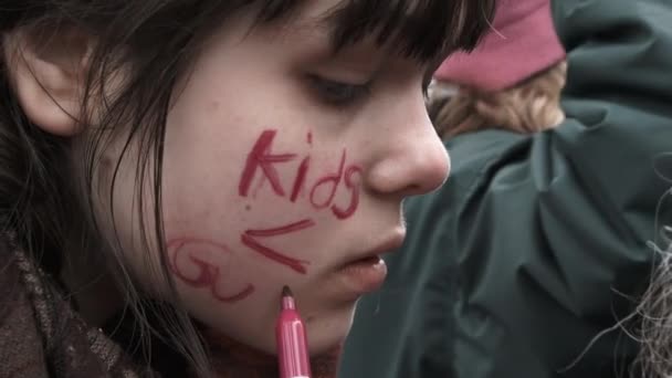 女の子は私たちの生活のために3月に子供たちに対する暴力を禁止するために抗議して彼女の顔に書きます — ストック動画