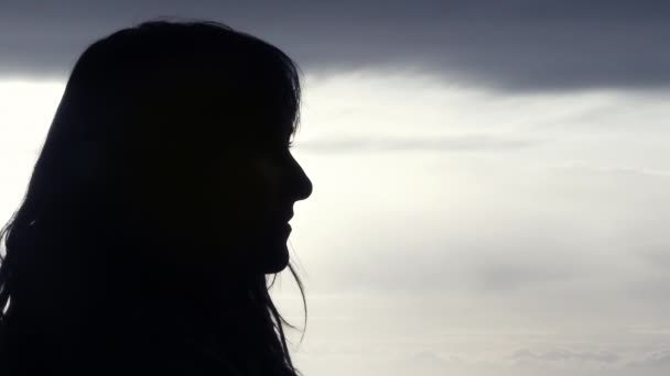 一个女人的轮廓被风吹着她的头发和云彩的背影 动作缓慢 — 图库视频影像