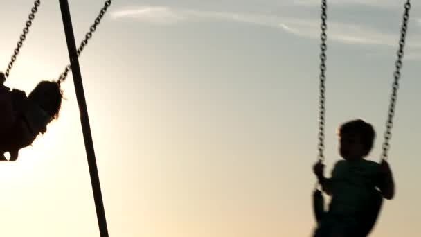 Brother Sister Silhouetted While Playing Swings Sunny Day — Stock Video