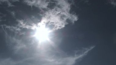 İnce bulut tabakası mavi gökyüzünden geçerken güneş sıcacık ve parlak vuruyor. Daha dramatik bir etki yaratmak için hızlan..