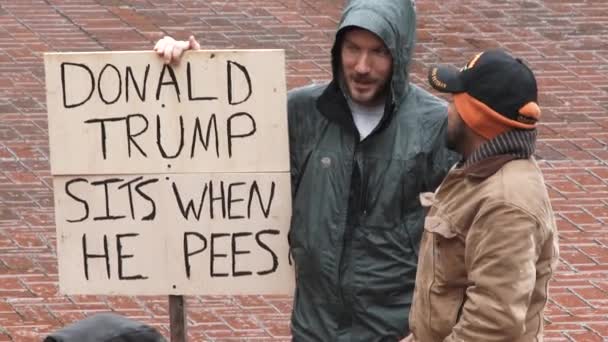 Man with Donald Trump Sits When He Pees sign protests on inauguration day at Pioneer Courthouse Square. — Stock Footage Man Donald Trump Sits Pees Sign Protests Inauguration Day Pioneer Video Clip