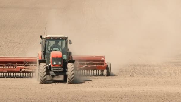 オレゴン州の暑い風の強い日に 農家は赤いトラクターを運転して土壌を耕し 新しい作物の準備をします — ストック動画