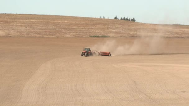オレゴン州の農場で土壌を耕す赤いトラクターの広いショット — ストック動画