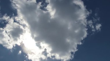 Büyük bulutlar geçer ve mavi gökyüzünde parlayan parlak güneşi açığa çıkarır..