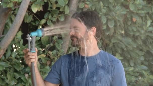 在炎热的夏天 模特的慢动作让男人在外面用软管喷自己的脸 — 图库视频影像