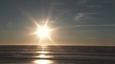 Güzel ve güneşli bir günde Oregon Sahili 'nden Pasifik Okyanusu' nun üzerinde gün batımı kadar gerçek zamanlı plaj manzarası..