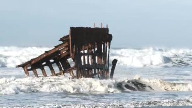 Peter Iredale 'in enkazı Oregon sahilinde Pasifik Mezarlığı' nda, Stevens Kalesi 'nde dalgalara maruz kaldı..