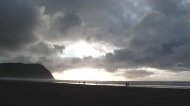 Gün batımında deniz kenarındaki Oregon Sahili 'nde bulutların dağılması insanlara ışık verir..