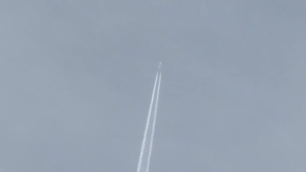 飛行機は薄曇りの青い空の日にフレームを通って頭上を飛ぶ蒸気トレイルジェットコンクールの後ろを離れる — ストック動画
