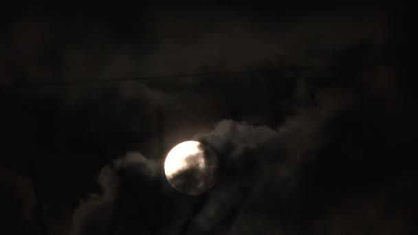 Pleine lune apparaissant et disparaissant sur un ciel nocturne sombre et nuageux .