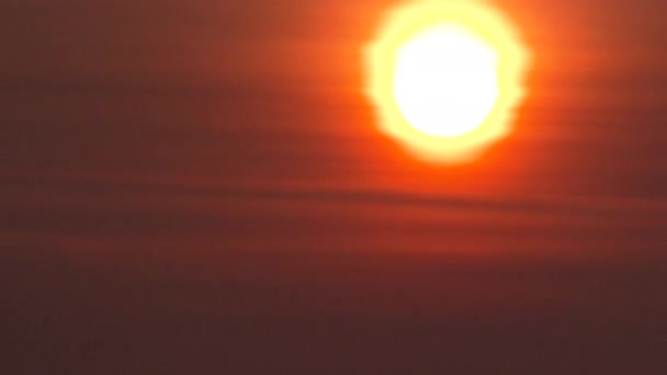 4K Soleil rouge vif se couchant à travers la couche nuageuse le soir brumeux .