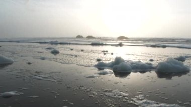 Oregon sahilindeki kumlu sahilde deniz köpüğü kıyıya vurur..