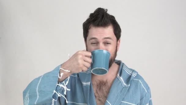 モデルリリース男でスタジオ楽しむコーヒーカップで午前中にまだ彼のローブ 2クリップシーケンス — ストック動画
