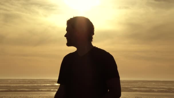 Człowiek Stoi Oceanie Spokojnym Zakładając Okulary Przeciwsłoneczne Idąc Kierunku Kamery — Wideo stockowe