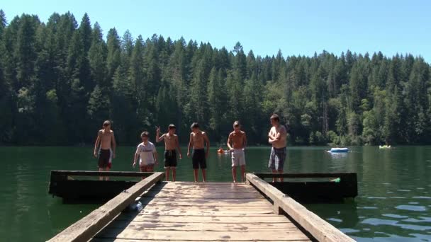 在炎热的夏天 一群孩子从华盛顿州美丽的湖面上的木制码头上跳了下来 — 图库视频影像
