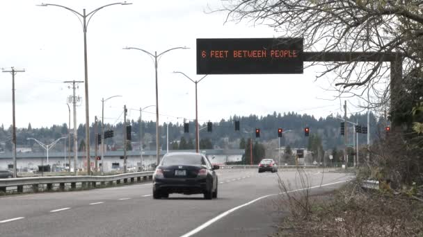 当车辆驶过空旷的街道时 电子路标上写着 保持距离 人与人之间6英尺 — 图库视频影像