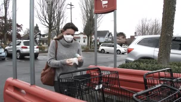 顔のマスクを身に着けている女性はショッピングカートまで歩き Covid 19危機の間に食料品店に入る前にそれを消毒する — ストック動画