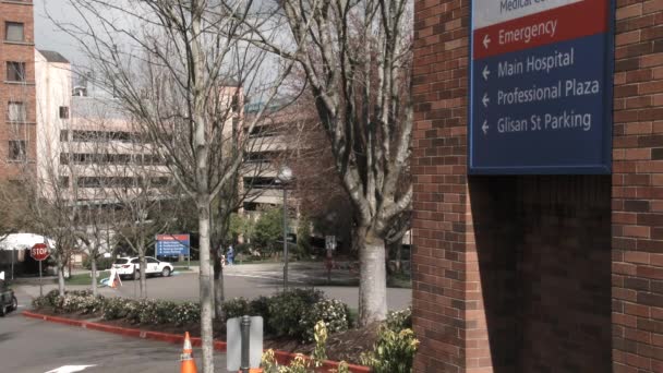 駐車場へ患者を誘導する看板付きの外観の大きな病院棟 — ストック動画