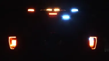 Gece ışıkları yanıp sönen bir polis arabasıyla yüz yüze..