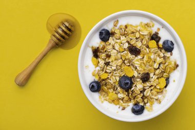 Sarı arka planda yoğurtlu müsli.