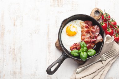 Beyaz arka planda pastırmalı sahanda yumurta.