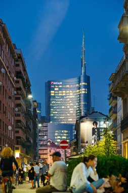 Milan, İtalya - 28 Eylül 2016: Unicredit gökdelen Gae Aulenti square, yeni finalcial bölge. Corso Garibaldi gün batımından yönü ön planda bulanık insanlarla görüntülemek.