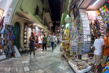 Otranto, İtalya - 11 Ağustos 2015: Hatıra Eşyası dükkanı ve torists akşam şehrin dar sokaklarında içinde.