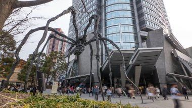 Tokyo, Japonya - Mart, 2017 yaklaşık: Louise Bourgeois örümcek heykel Roppongi içinde altında yürüyen insanlar. 