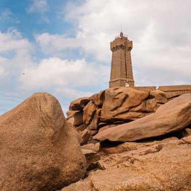 Ploumanac'h lighthouse against blue cloudy sky. It is an active lighthouse in Cotes-d'Armor, France, located in Perros-Guirec. The structure is composed of pink granite.  clipart