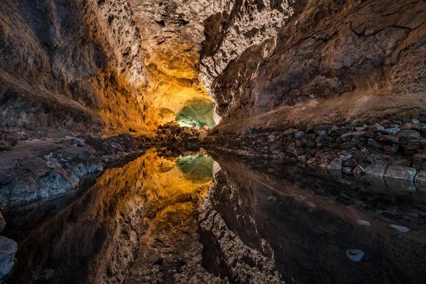 芒在西班牙兰萨罗特岛的一个惊人的熔岩管和旅游胜地 水反射导致光学幻觉 — 图库照片