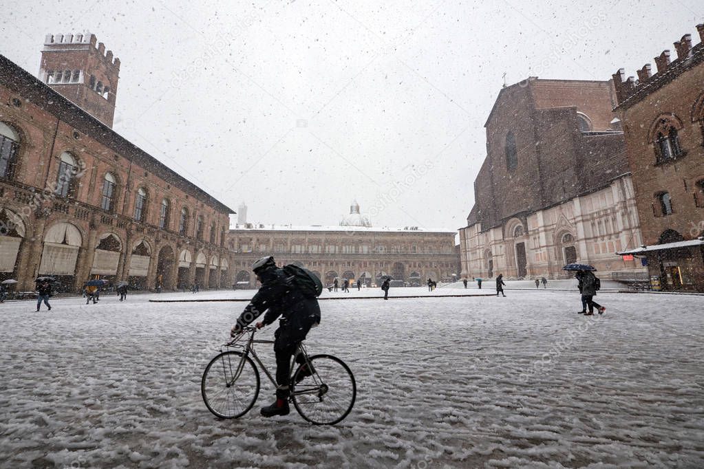 Man riding bicycle in Maggiore square under the snow. Bologna, Italy. 