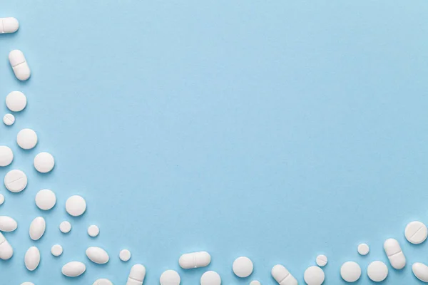 Pílulas médicas brancas em fundo azul — Fotografia de Stock