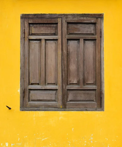 Fenêtre en bois marron sur mur jaune à Hoi An — Photo