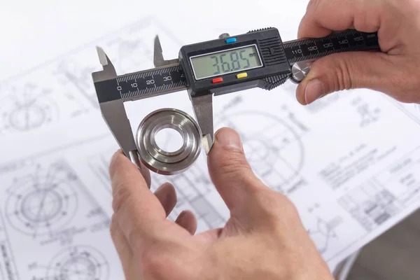 Händer av en ingenjör mäter en metalldel med en digital vernie — Stockfoto
