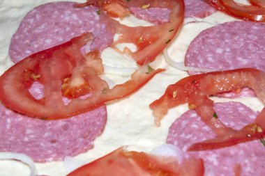 Jambonlu ve domatesli bir dilim pizzanın arka planı. Yemek pişirme sürecinde bir dilim pizza. Yukarıdan bak. arkaplan