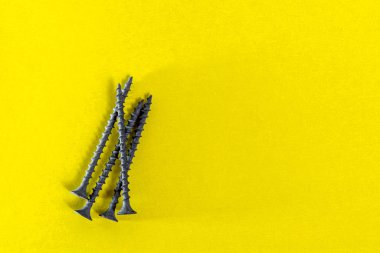 Sarı arka planda vidalar. Vidaları kapat. Uzayı kopyala Sertleştiren tahta vidalar.