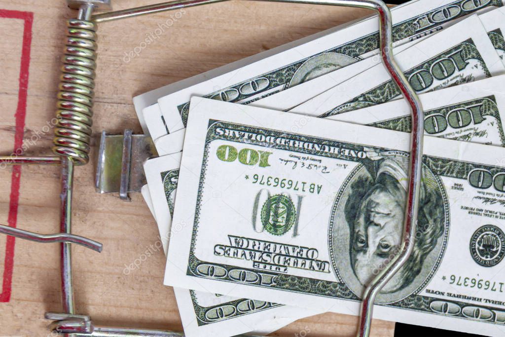 American dollar bills in a mousetrap close up. Concept: financial trap, lending, debt.