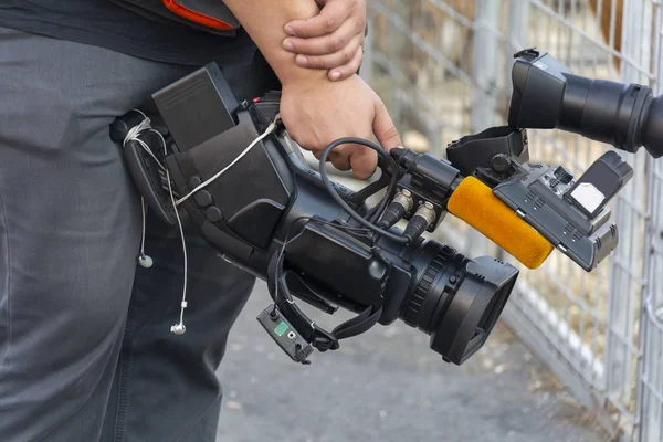 Videocamera nelle mani di un uomo primo piano. L'operatore della telecamera lavora con la sua attrezzatura. Concetto: sparatoria di reportage, notizie, lavoro di giornalisti . — Foto Stock