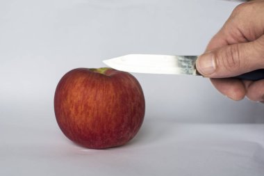 Adam kırmızı elmayı bıçakla kesiyor.