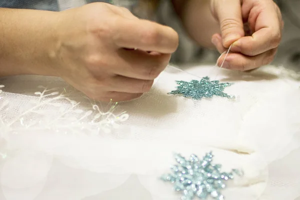 Tatil için elbiseye kar taneleri dikiyorum. El yapımı elbise. Moda tasarımı. Güzel dikiş çiçeği. İşteki tasarımcı